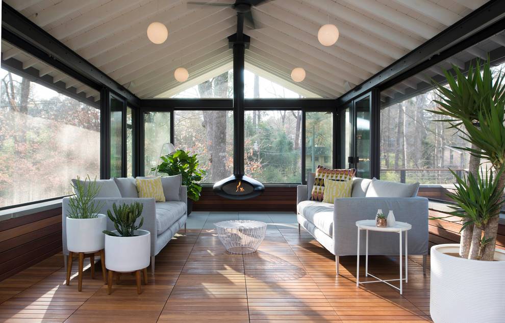 Photo of a midcentury sunroom in Raleigh with medium hardwood floors and a hanging fireplace.