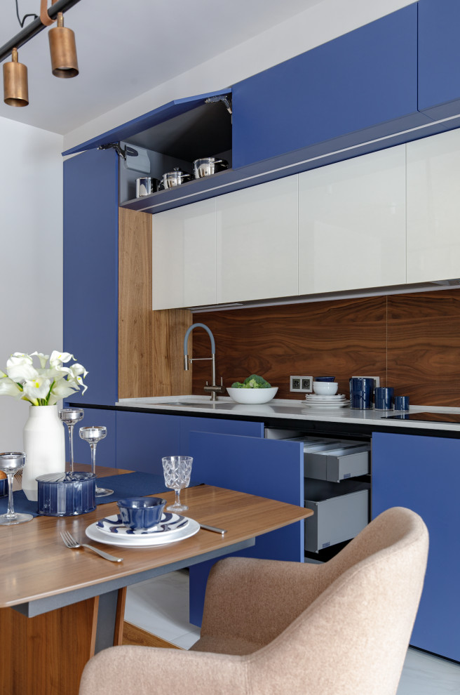 This is an example of a mid-sized contemporary single-wall eat-in kitchen in Moscow with a single-bowl sink, blue cabinets, quartz benchtops, brown splashback, timber splashback, panelled appliances, no island and white benchtop.