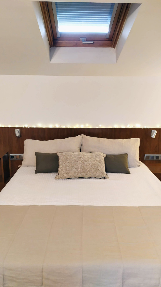Modelo de dormitorio principal, blanco y beige y blanco contemporáneo con paredes blancas, suelo de madera en tonos medios y techo inclinado