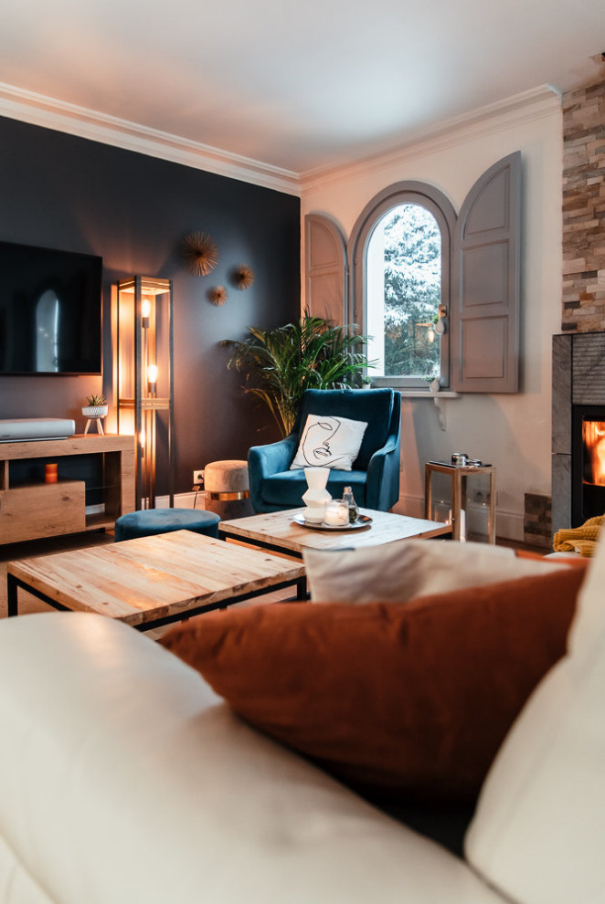 Foto di un soggiorno tradizionale di medie dimensioni e chiuso con pareti grigie, parquet chiaro, stufa a legna e TV a parete