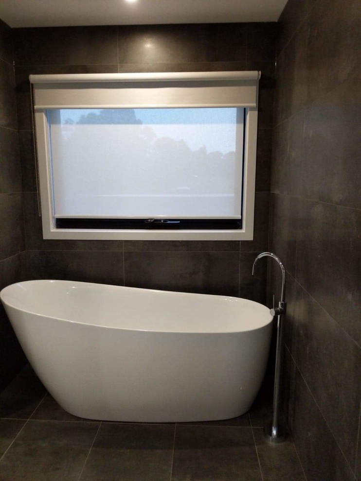 Design ideas for a mid-sized modern master bathroom in Melbourne with flat-panel cabinets, white cabinets, a freestanding tub, a double shower, gray tile, porcelain tile, beige walls, porcelain floors, a vessel sink, laminate benchtops, grey floor, an open shower and white benchtops.