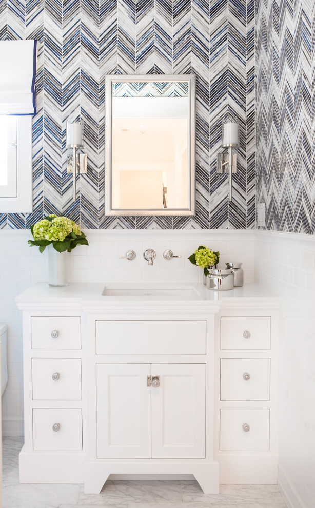 This is an example of a small transitional powder room in Los Angeles with recessed-panel cabinets, white cabinets, a one-piece toilet, blue tile, mosaic tile, marble floors, an undermount sink and engineered quartz benchtops.