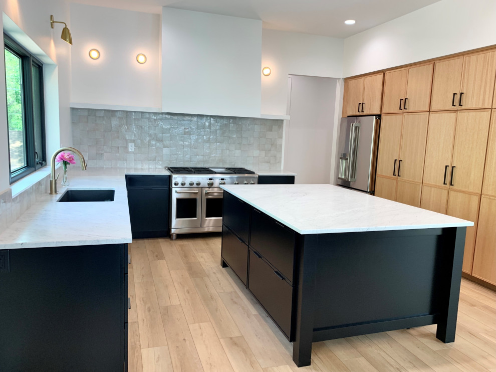 Foto på ett stort minimalistiskt vit kök, med en undermonterad diskho, skåp i shakerstil, svarta skåp, marmorbänkskiva, flerfärgad stänkskydd, rostfria vitvaror, vinylgolv, en köksö och brunt golv