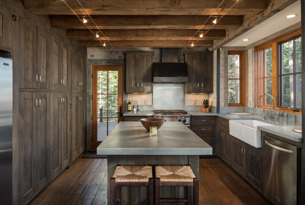 This is an example of a mid-sized country l-shaped separate kitchen in Denver with a farmhouse sink, shaker cabinets, dark wood cabinets, stainless steel appliances, dark hardwood floors, with island, brown floor, grey benchtop and concrete benchtops.