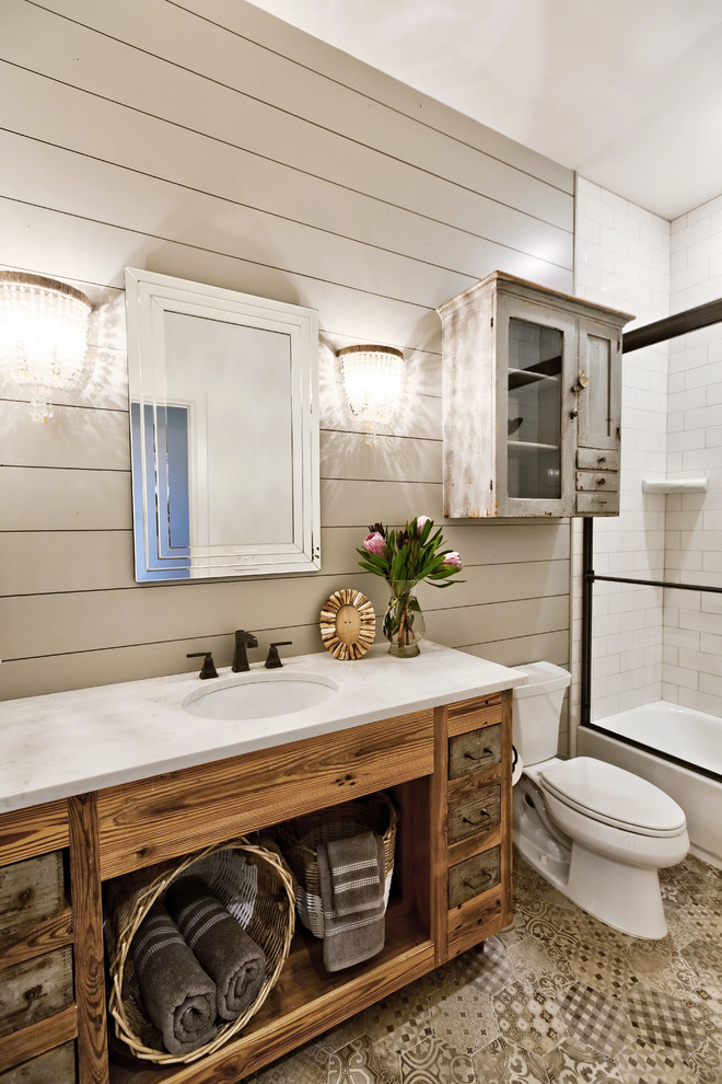 Inspiration for a country 3/4 bathroom in Oklahoma City with furniture-like cabinets, distressed cabinets, an alcove tub, a shower/bathtub combo, a two-piece toilet, white tile, porcelain tile, grey walls, ceramic floors, an undermount sink, engineered quartz benchtops, multi-coloured floor and a sliding shower screen.