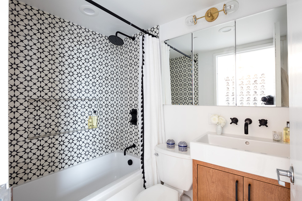Design ideas for an eclectic master bathroom in New York with flat-panel cabinets, medium wood cabinets, an alcove tub, a shower/bathtub combo, white tile, cement tile, white walls, a trough sink and a shower curtain.