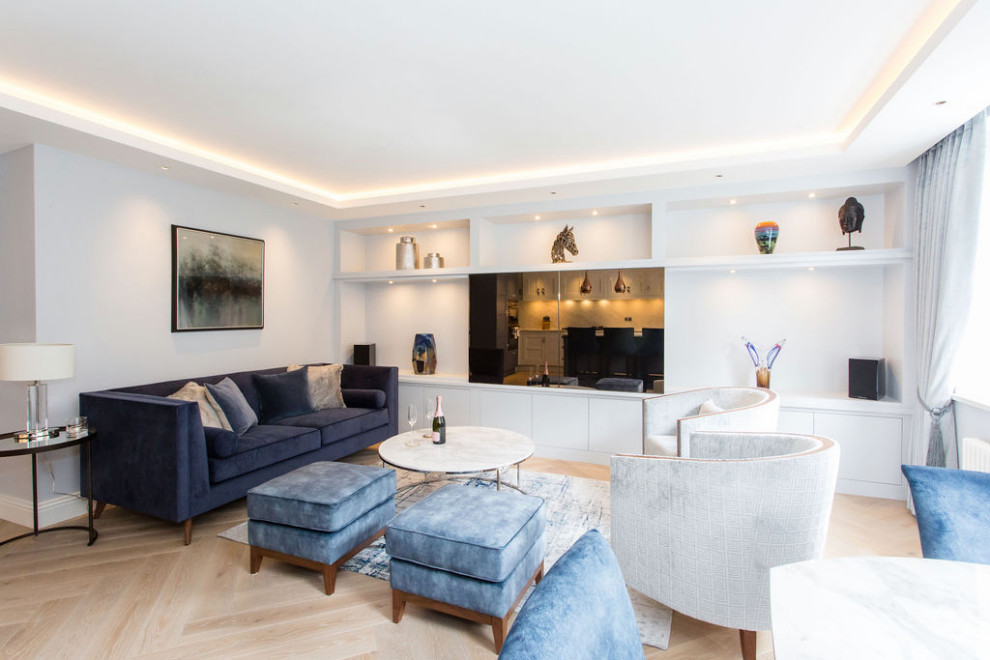 This is an example of a mid-sized contemporary formal open concept living room in London with blue walls, light hardwood floors and a built-in media wall.