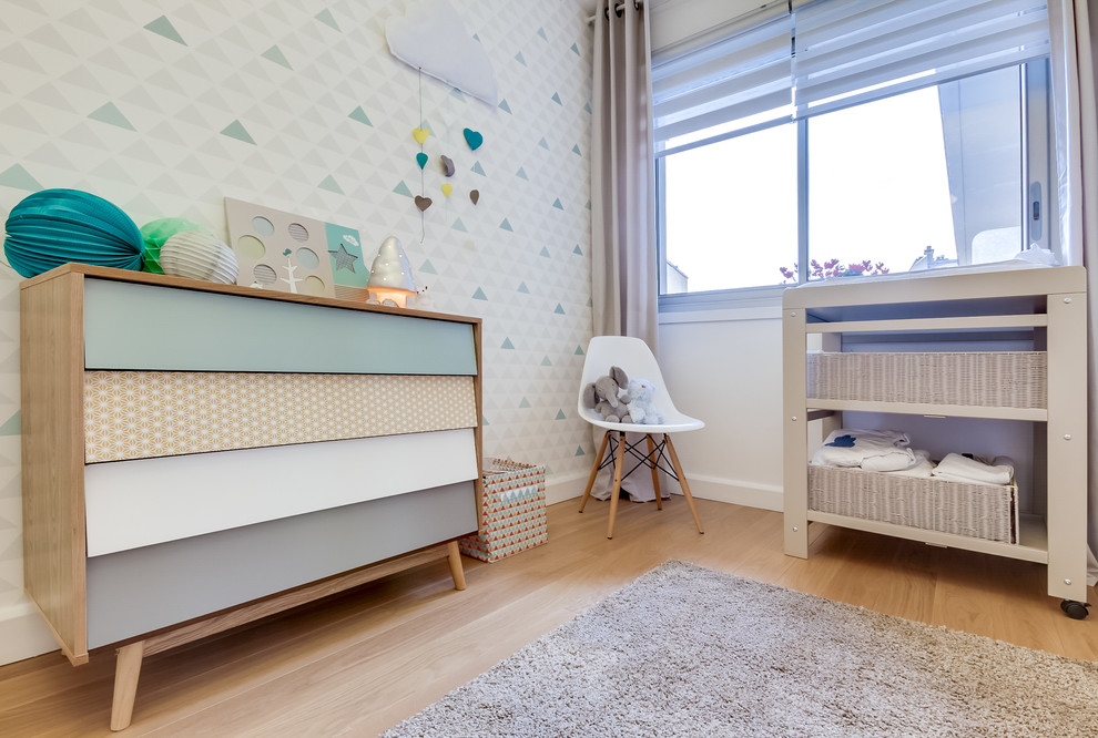 Photo of a mid-sized scandinavian gender-neutral nursery in Paris with white walls, light hardwood floors and beige floor.
