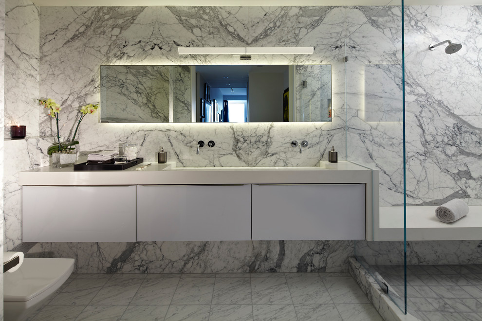 Design ideas for a mid-sized contemporary master bathroom in Los Angeles with a trough sink, flat-panel cabinets, white cabinets, an alcove shower, white tile, engineered quartz benchtops, a wall-mount toilet, white walls, marble floors, marble, grey floor and white benchtops.