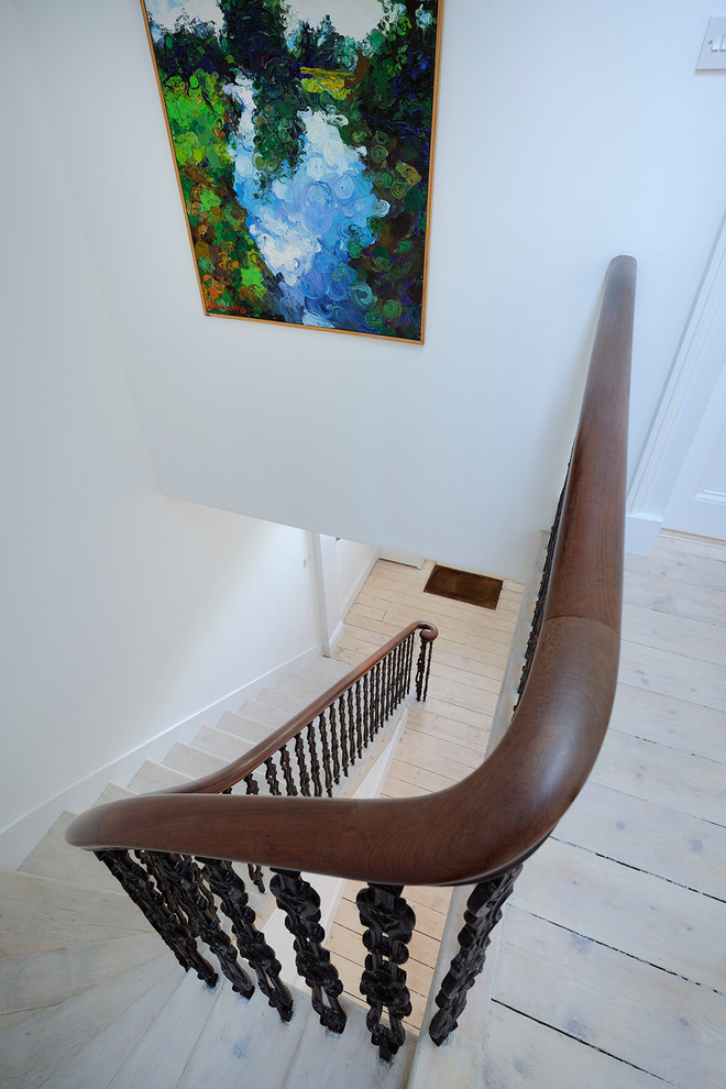 Photo of a large scandinavian wood curved staircase in Other with wood risers.