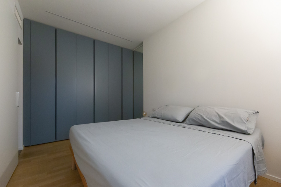Kleines Modernes Hauptschlafzimmer mit weißer Wandfarbe, hellem Holzboden, gelbem Boden und eingelassener Decke in Mailand