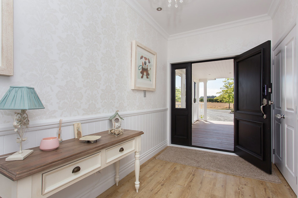 Photo of a Large country front door in Christchurch With White Walls, Light Hardwood Floors, a Pivot Front Door, a Dark Wood Front Door and Brown Floor.