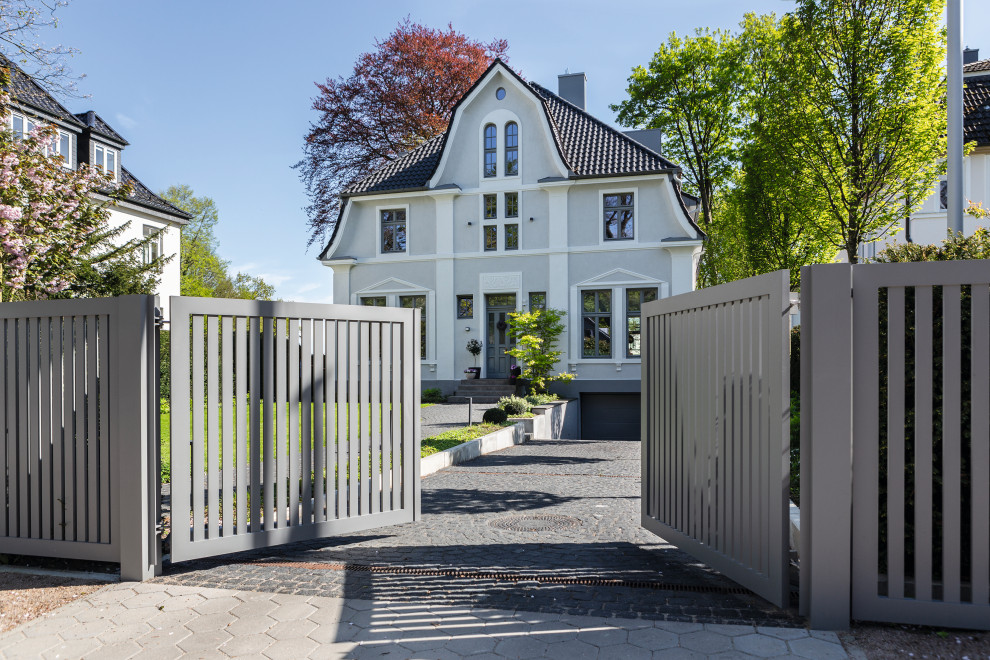 Großer Skandinavischer Garten im Frühling mit Auffahrt, direkter Sonneneinstrahlung, Natursteinplatten und Metallzaun in Hamburg