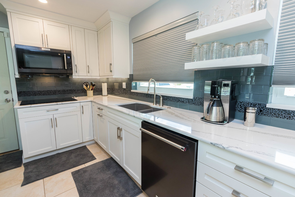 Example of a mid-sized transitional galley ceramic tile open concept kitchen design in Miami with a single-bowl sink, shaker cabinets, white cabinets, quartz countertops, black backsplash, glass tile backsplash, black appliances and a peninsula