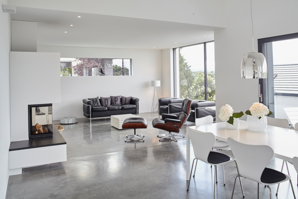 Modernes Wohnzimmer mit weißer Wandfarbe, Betonboden, Kaminofen, verputzter Kaminumrandung und grauem Boden in Stuttgart