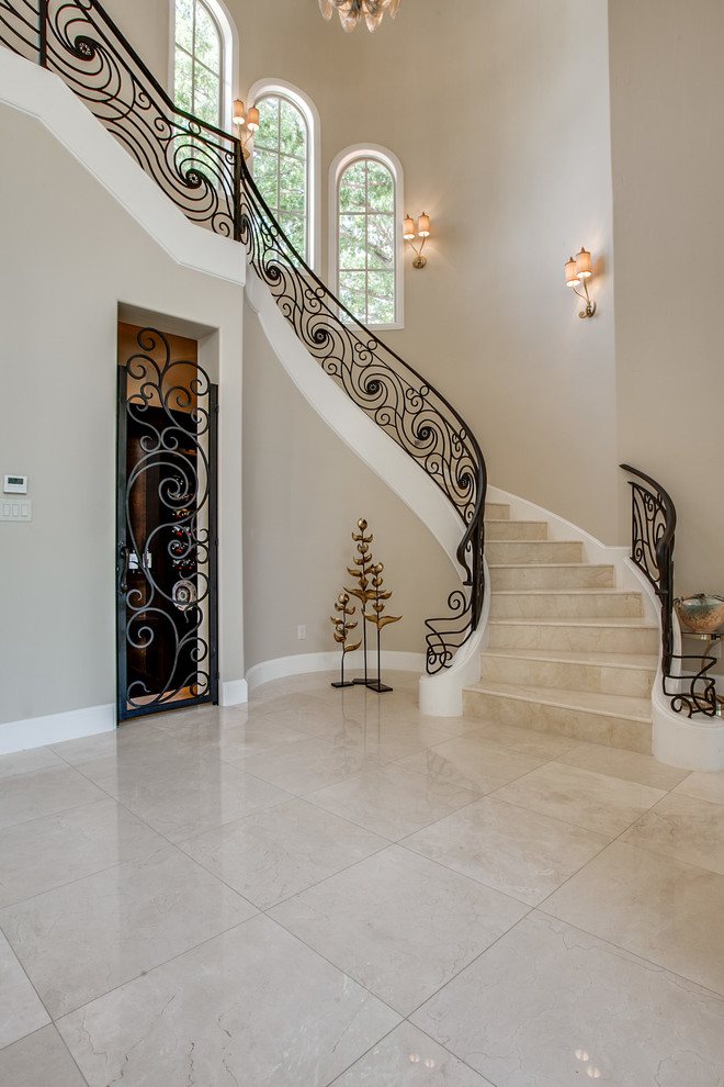 This is an example of a mediterranean travertine curved staircase in Dallas with travertine risers and metal railing.