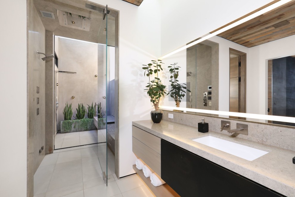 Inspiration for a mid-sized contemporary master bathroom in Orange County with flat-panel cabinets, gray tile, stone slab, white walls, an undermount sink, a hinged shower door, grey benchtops, grey cabinets, a curbless shower, porcelain floors, granite benchtops and beige floor.