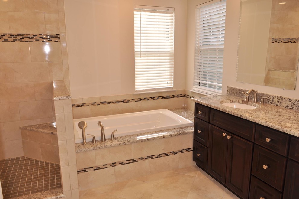 Example of a large transitional master beige tile and porcelain tile porcelain tile drop-in bathtub design in DC Metro with a drop-in sink, raised-panel cabinets, dark wood cabinets, granite countertops and beige walls