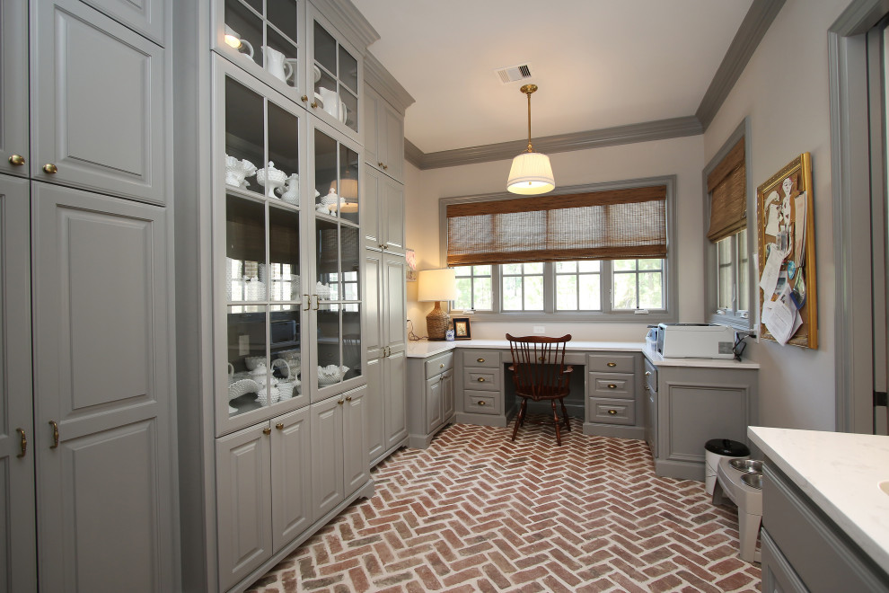 Design ideas for a large traditional u-shaped utility room in Houston with grey walls, brick floors, red floor, an undermount sink, raised-panel cabinets, grey cabinets, white splashback, subway tile splashback, a side-by-side washer and dryer and white benchtop.