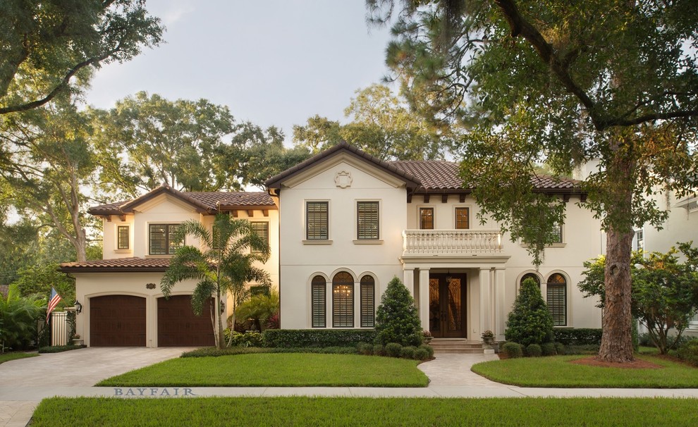Large mediterranean two-storey stucco beige house exterior in Tampa with a hip roof and a tile roof.