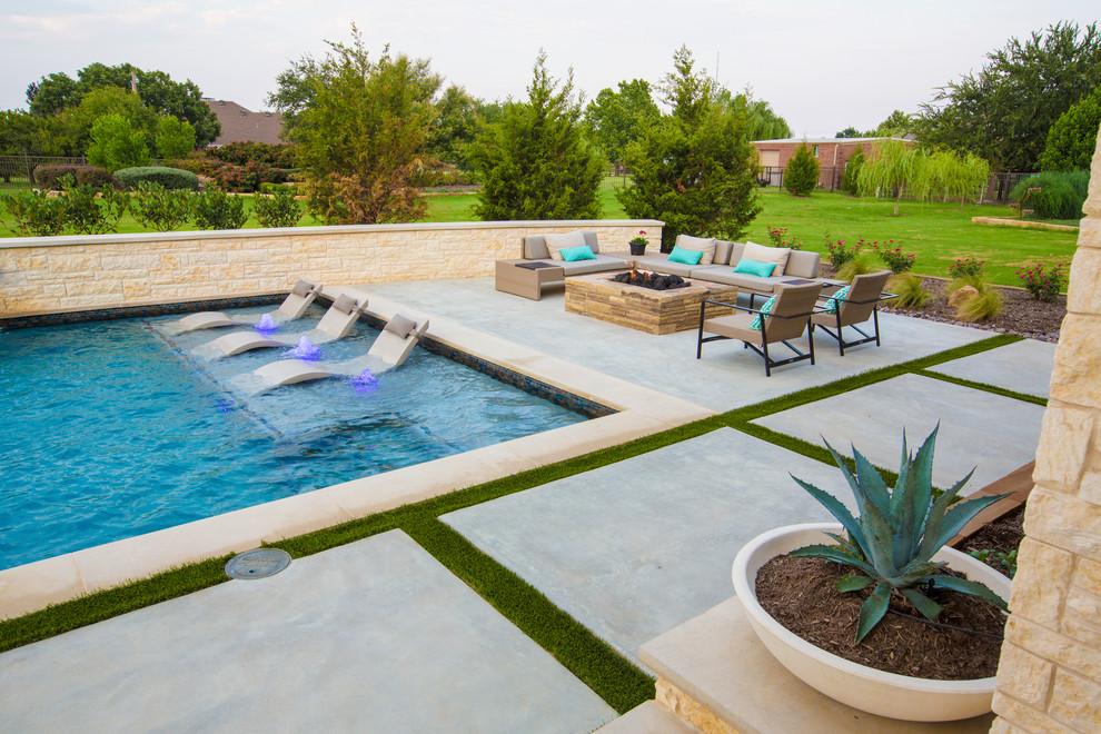 This is an example of a large contemporary backyard l-shaped pool in Dallas with concrete slab.
