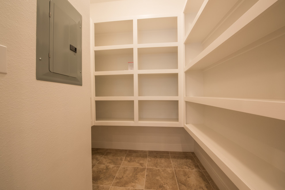This is an example of a mid-sized traditional gender-neutral storage and wardrobe in Houston with white cabinets and ceramic floors.