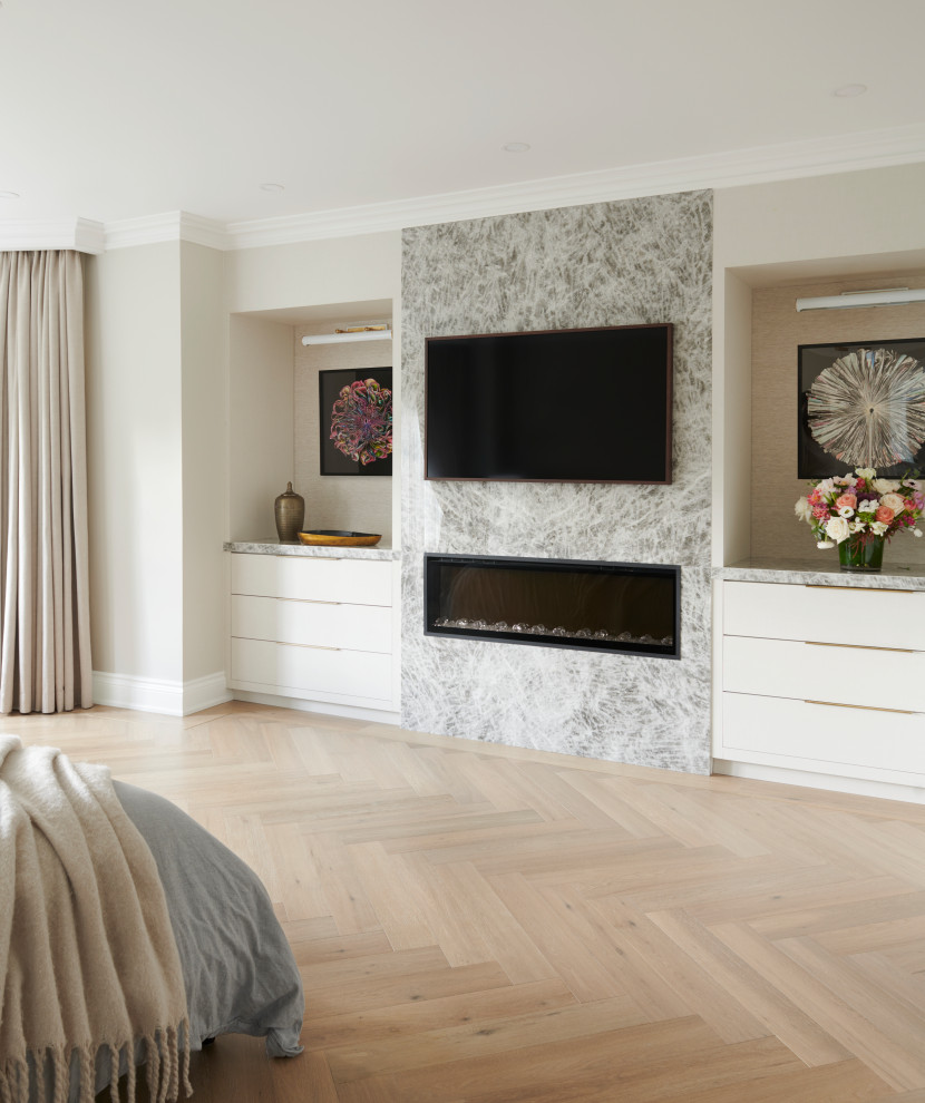 Design ideas for a large contemporary master bedroom in Toronto with beige walls, light hardwood floors, a standard fireplace, a stone fireplace surround and beige floor.