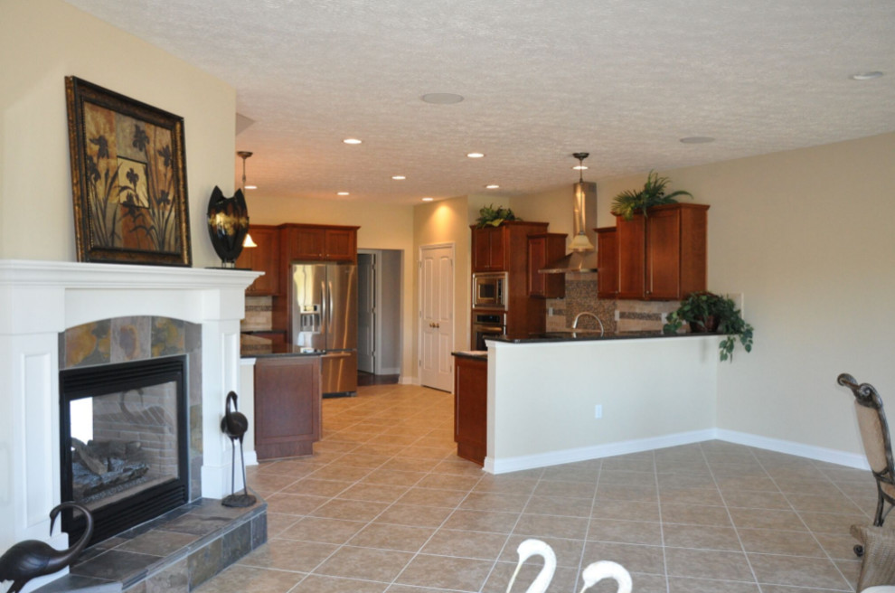 Mid-sized elegant l-shaped porcelain tile and beige floor open concept kitchen photo with a double-bowl sink, shaker cabinets, brown cabinets, granite countertops, beige backsplash, porcelain backsplash and stainless steel appliances