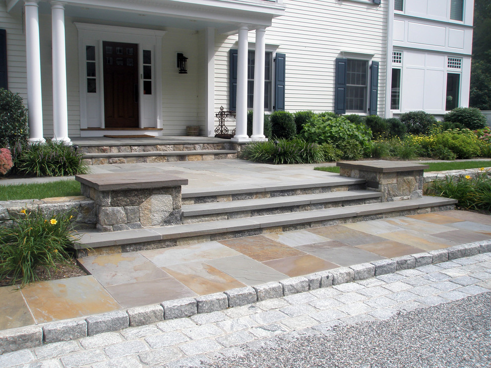 Photo of a large traditional front yard full sun driveway for spring in New York with a retaining wall and gravel.
