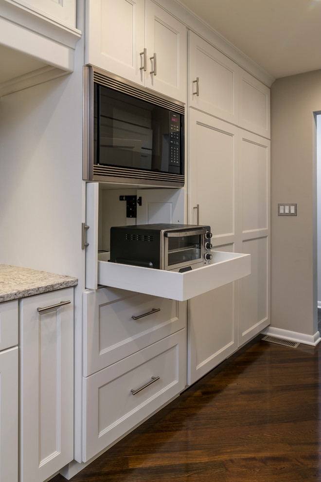 Example of a mid-sized transitional galley medium tone wood floor home design design in Chicago with an undermount sink, flat-panel cabinets, white cabinets, quartz countertops, beige backsplash, glass tile backsplash, paneled appliances and a peninsula
