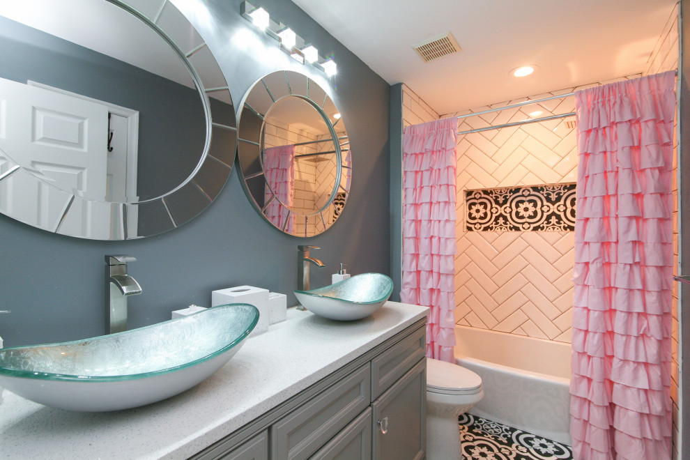 Inspiration for a transitional kids bathroom in Philadelphia with recessed-panel cabinets, grey cabinets, an alcove tub, a shower/bathtub combo, white tile, grey walls, a vessel sink, multi-coloured floor, a shower curtain, white benchtops, a double vanity and a built-in vanity.