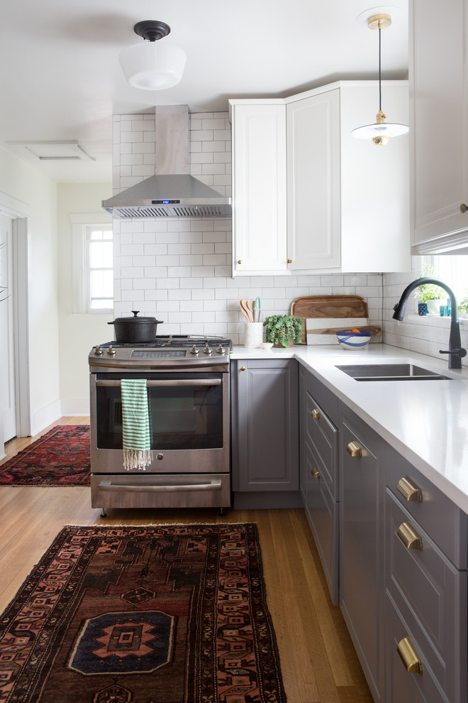 This is an example of a transitional kitchen in Denver with an undermount sink, raised-panel cabinets, grey cabinets, white splashback, subway tile splashback, medium hardwood floors and brown floor.