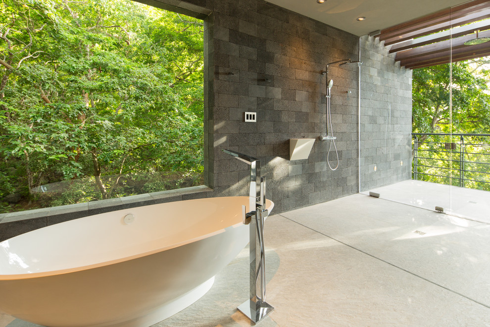 Large contemporary master bathroom in Other with flat-panel cabinets, grey cabinets, a freestanding tub, an open shower, a wall-mount toilet, gray tile, stone tile, white walls, porcelain floors, an undermount sink, solid surface benchtops, grey floor, an open shower and white benchtops.