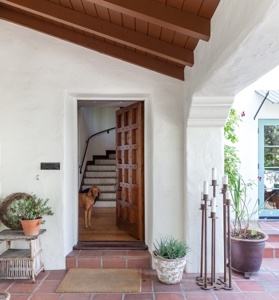This is an example of a large mediterranean front door in Sacramento with white walls, terra-cotta floors, a single front door and a dark wood front door.