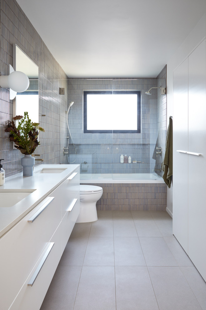 Inspiration for a mid-sized modern kids' blue tile and ceramic tile porcelain tile, gray floor and double-sink bathroom remodel in San Francisco with flat-panel cabinets, white cabinets, a one-piece toilet, white walls, an undermount sink, quartz countertops, a hinged shower door, gray countertops and a floating vanity