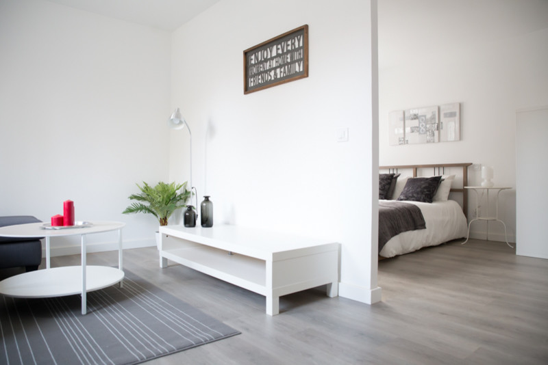This is an example of a small scandinavian open concept living room in Madrid with white walls and light hardwood floors.