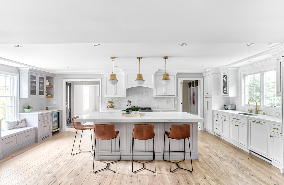Photo of a large transitional u-shaped eat-in kitchen in New York with an undermount sink, beaded inset cabinets, white cabinets, quartz benchtops, white splashback, mosaic tile splashback, panelled appliances, with island and white benchtop.