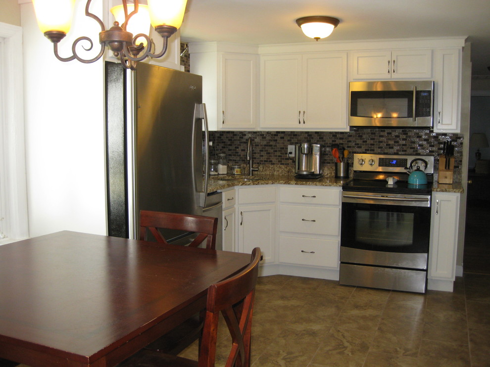 Inspiration for a small transitional l-shaped porcelain tile and brown floor kitchen remodel in Boston with an undermount sink, recessed-panel cabinets, white cabinets, granite countertops, brown backsplash, stainless steel appliances, no island, glass tile backsplash and beige countertops