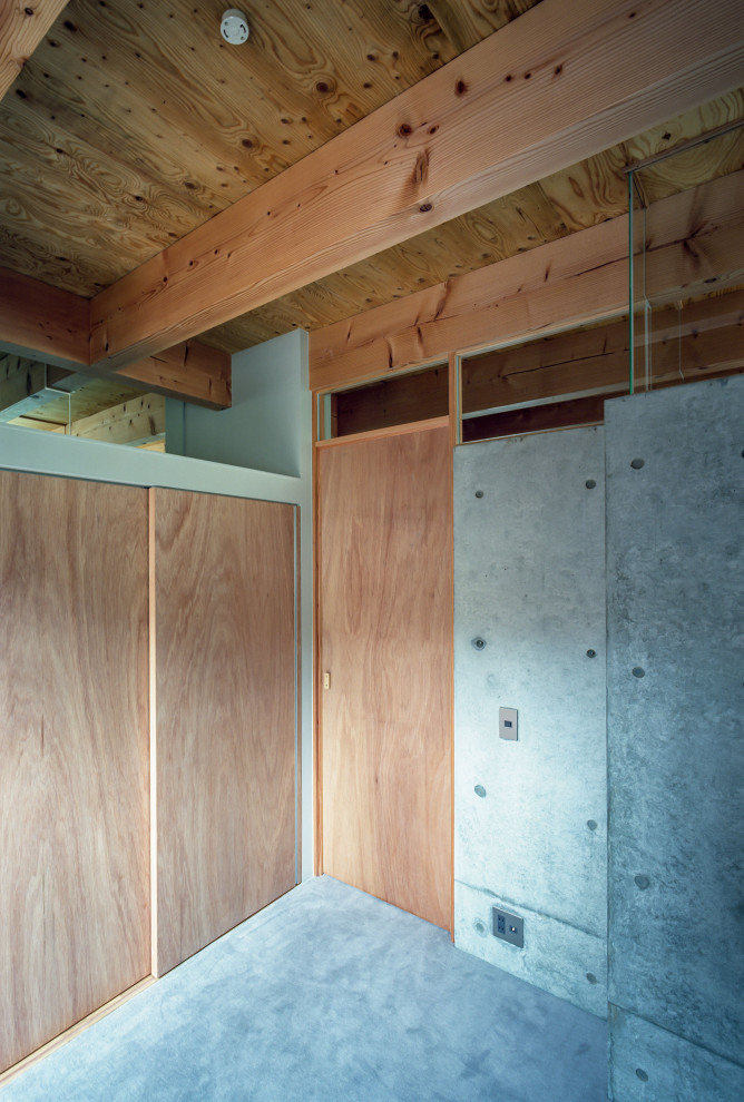 Aménagement d'une petite chambre moderne avec un mur gris, sol en béton ciré, un sol gris et poutres apparentes.