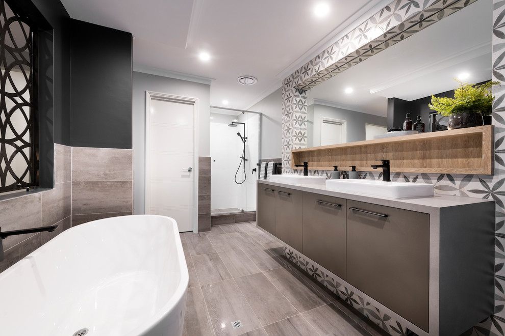 This is an example of a contemporary master bathroom in Perth with flat-panel cabinets, brown cabinets, a freestanding tub, a corner shower, beige tile, gray tile, multi-coloured walls, a vessel sink, grey floor, a hinged shower door and grey benchtops.