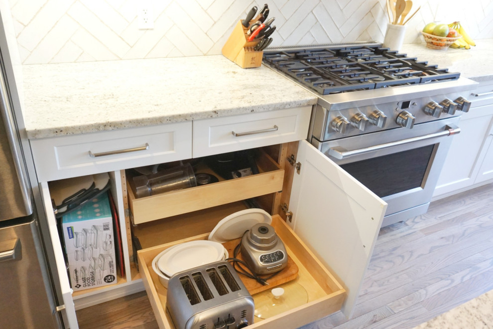 Example of a huge transitional light wood floor and brown floor eat-in kitchen design with an undermount sink, shaker cabinets, white cabinets, granite countertops, white backsplash, ceramic backsplash, stainless steel appliances, an island and white countertops