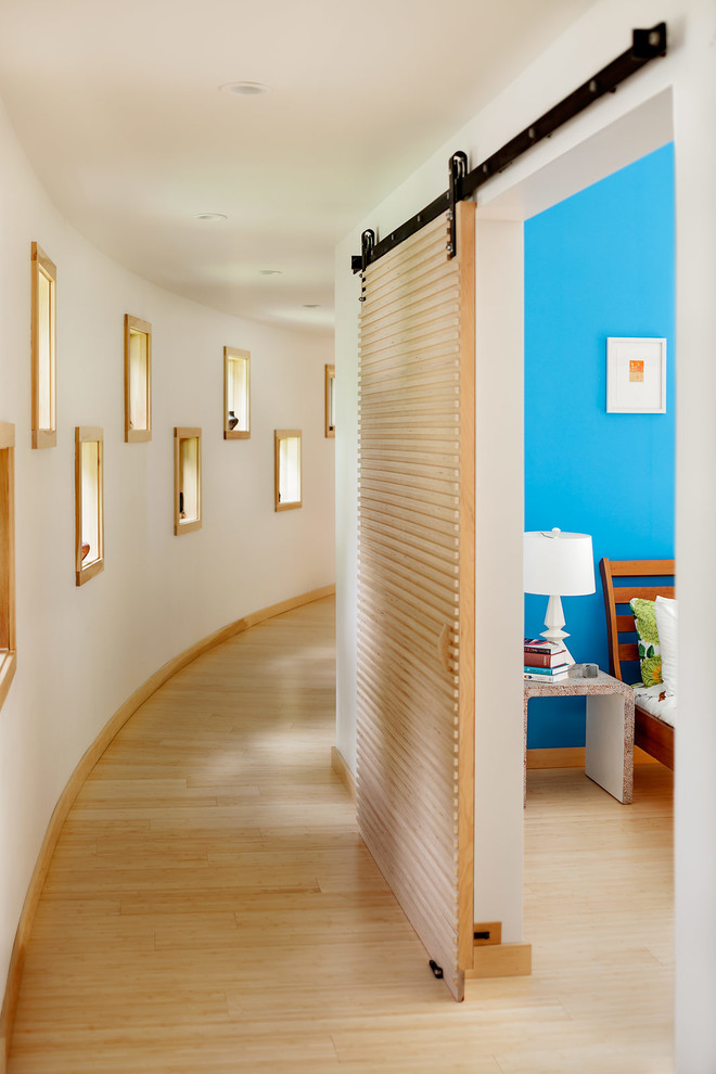 Contemporary hallway in Portland Maine with white walls and light hardwood floors.