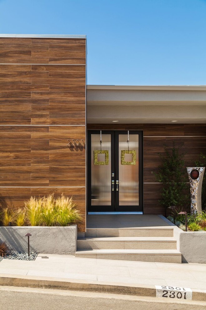 This is an example of a mid-sized midcentury split-level stucco grey exterior in Los Angeles.