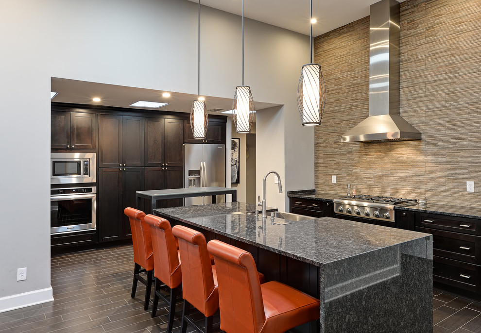 Inspiration for a large transitional u-shaped cement tile floor and brown floor open concept kitchen remodel in Jacksonville with a drop-in sink, flat-panel cabinets, black cabinets, granite countertops, multicolored backsplash, stone tile backsplash, stainless steel appliances and an island