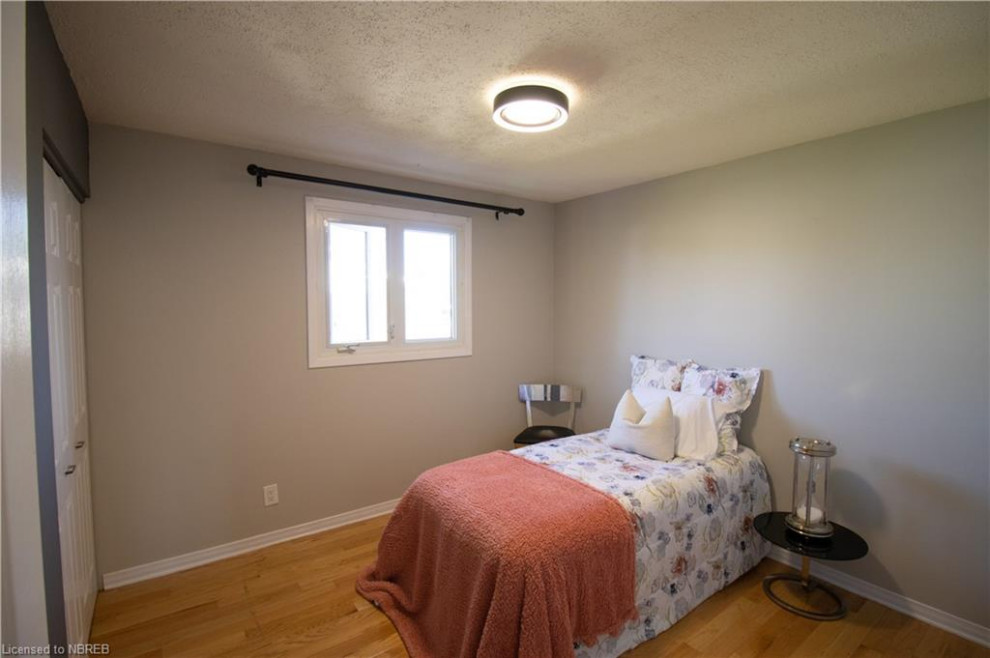 Immagine di una piccola camera degli ospiti contemporanea con pareti grigie, pavimento in legno massello medio e pavimento marrone