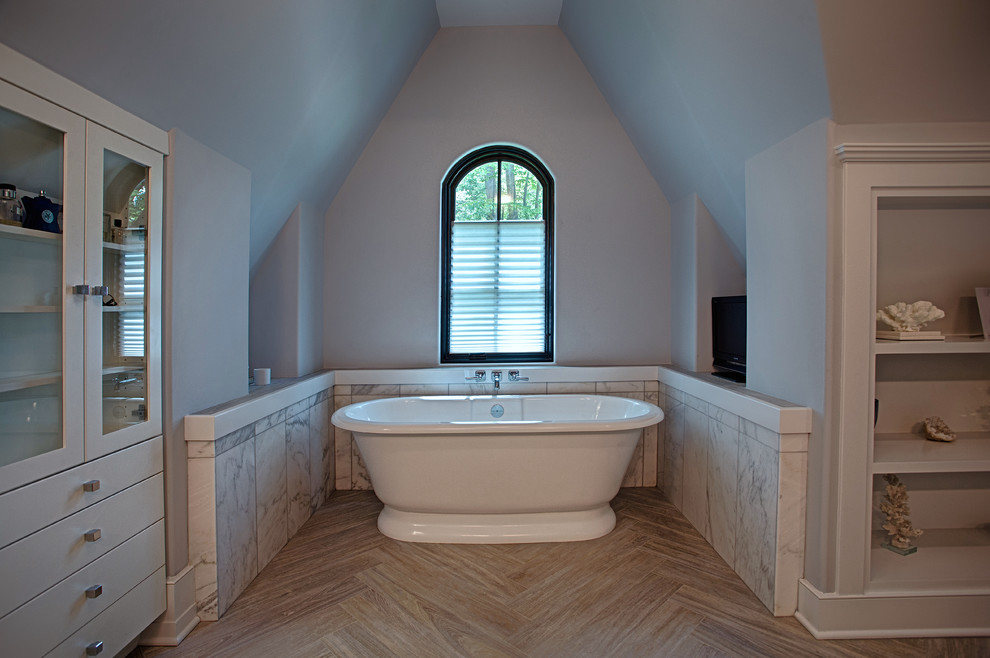 This is an example of a large transitional master bathroom in New York with flat-panel cabinets, white cabinets, a freestanding tub, a one-piece toilet, black and white tile, marble, white walls, light hardwood floors, an undermount sink, marble benchtops, beige floor, an alcove shower and a hinged shower door.