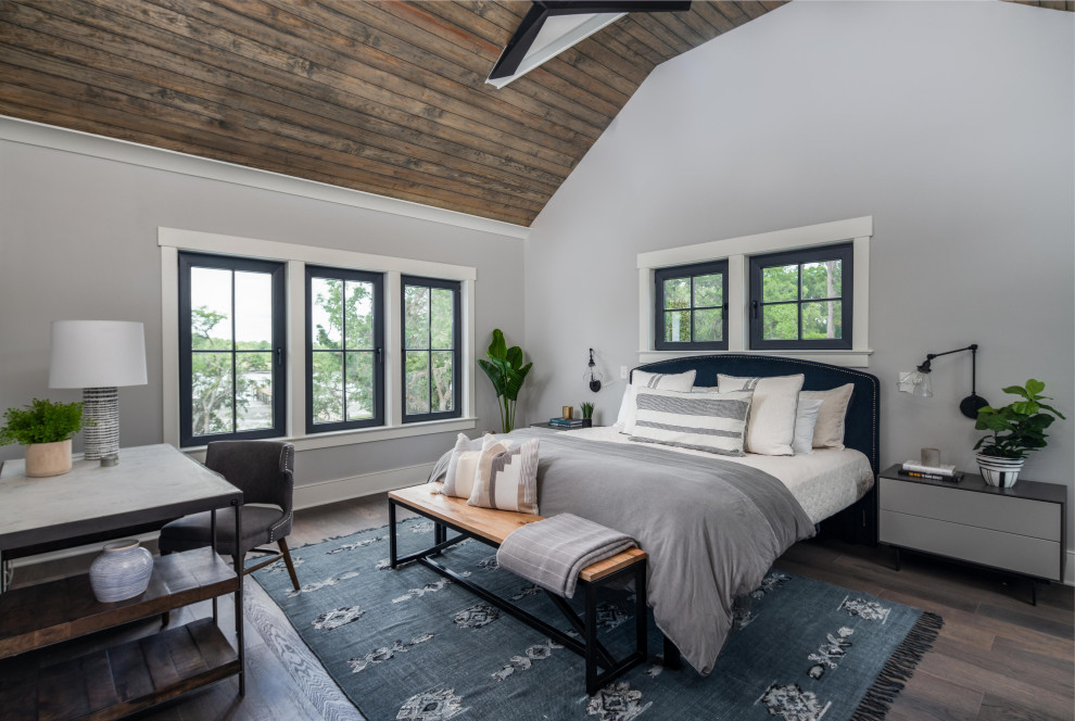 This is an example of a beach style master bedroom in Charleston with grey walls, dark hardwood floors, vaulted and wood.