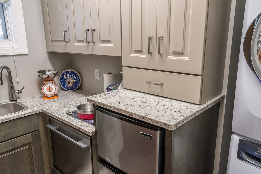 Small traditional l-shaped utility room in Other with a single-bowl sink, raised-panel cabinets, beige cabinets, granite benchtops, beige walls, ceramic floors, a stacked washer and dryer, beige floor and brown benchtop.