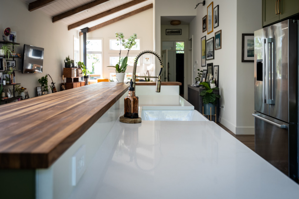 Inspiration for a mid-sized transitional l-shaped eat-in kitchen remodel with an undermount sink, shaker cabinets, green cabinets, quartz countertops, white backsplash, ceramic backsplash, stainless steel appliances, an island and white countertops