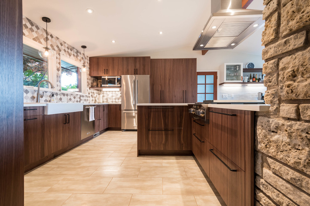 Photo of a large midcentury l-shaped eat-in kitchen in Seattle with a farmhouse sink, flat-panel cabinets, dark wood cabinets, quartz benchtops, beige splashback, mosaic tile splashback, stainless steel appliances, porcelain floors, a peninsula and beige floor.